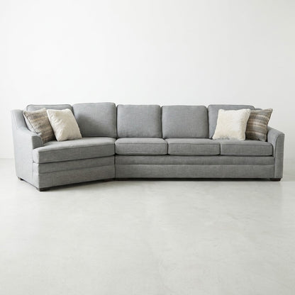 Gray sectional sofa with fluffy pillows on a white floor.