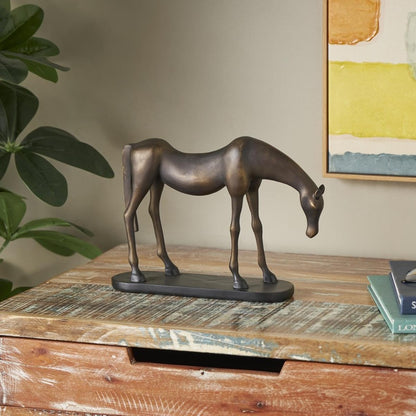 Bronze horse sculpture on rustic wooden table, with books and plant nearby.