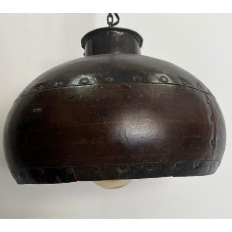 Vintage metal pendant light with rivets and a dark finish.