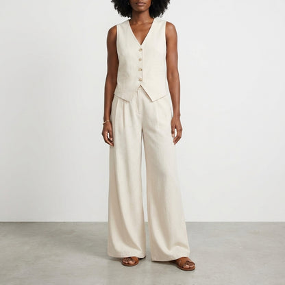 Woman in beige vest and pants ensemble, standing on gray floor.