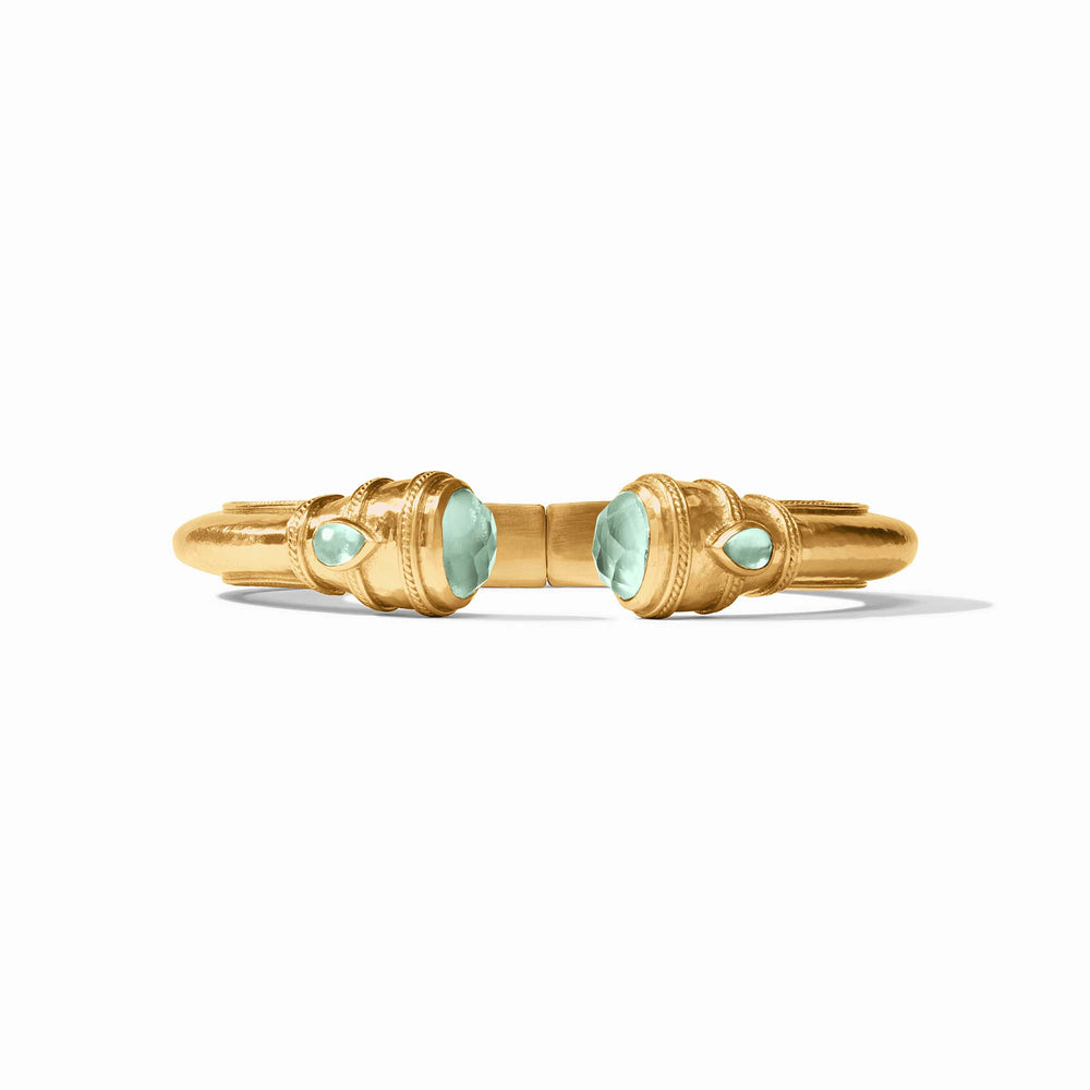 A gold ring with symmetrical aqua gemstones and ornate detailing on a white background.