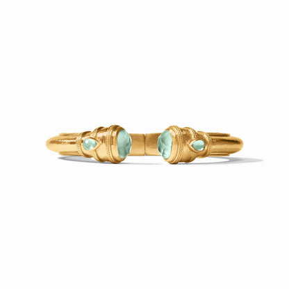 A gold ring with symmetrical aqua gemstones and ornate detailing on a white background.