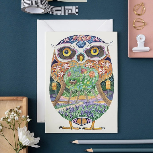 Colorful owl illustration on a card with stationery items, pencils, and flowers.