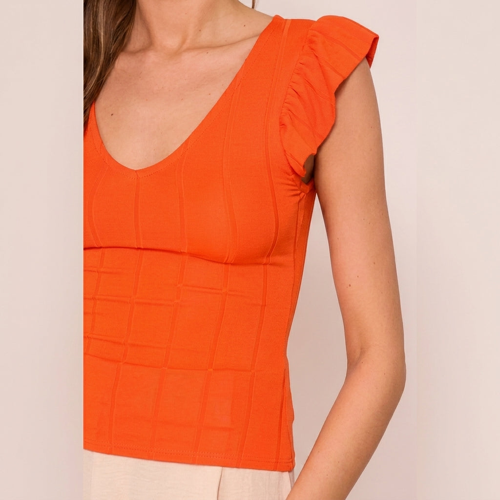 Woman in an orange top with ruffled sleeves.