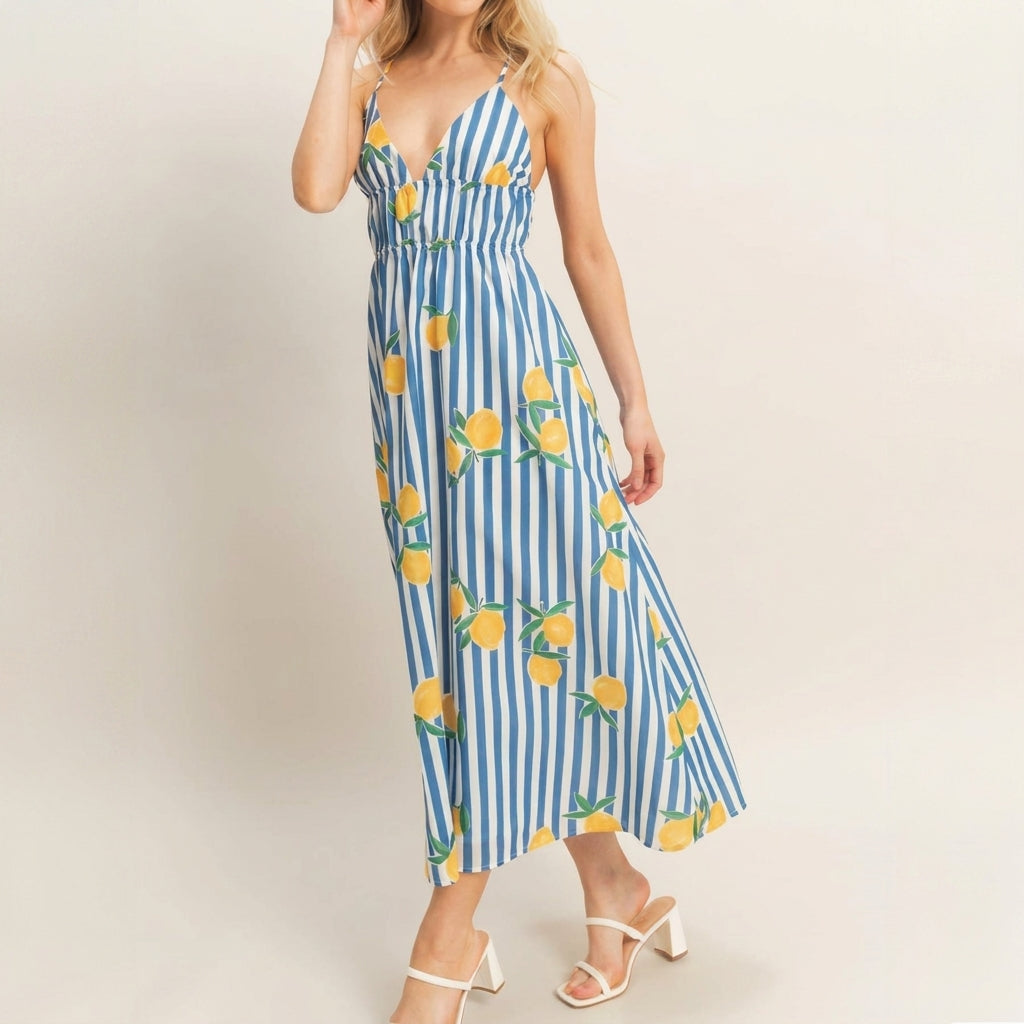 Woman in a striped dress with lemon print, wearing white sandals.