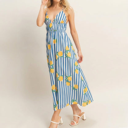 Woman in a striped dress with lemon print, wearing white sandals.