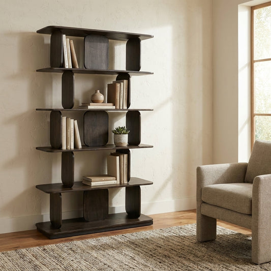 Modern bookshelf with books and decor next to a cozy armchair by a window.
