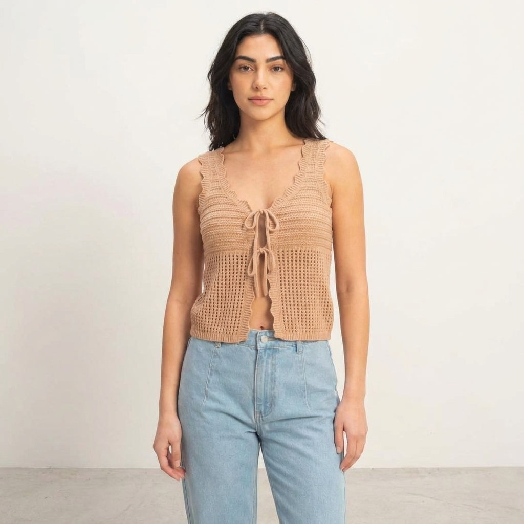 Woman in a crochet top and jeans against a neutral background.