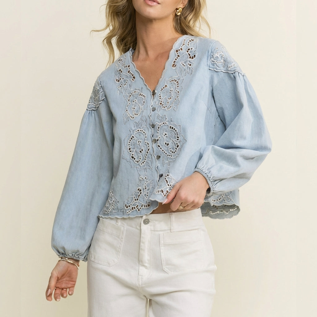 Woman in a blue embroidered blouse and white pants.