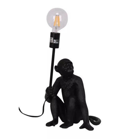 Monkey-shaped lamp holding a light bulb on a stick.