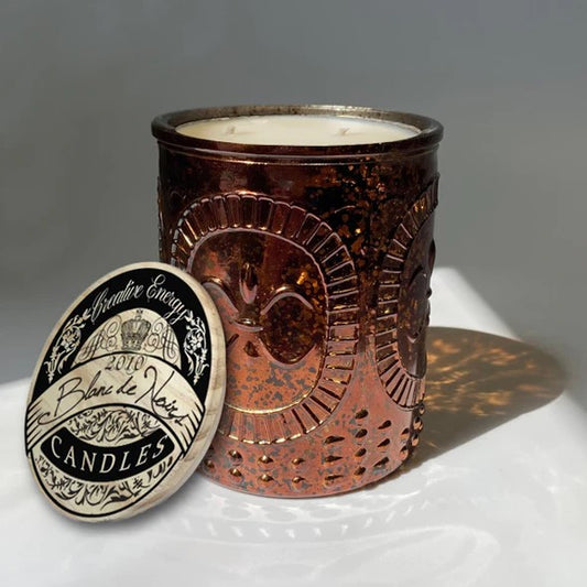 Bronze-textured candle holder with lid, casting a decorative shadow.