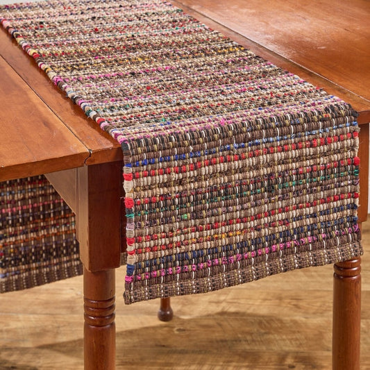 Wooden table with a colorful, woven table runner.