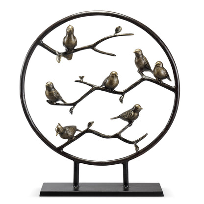 Metal sculpture of birds on branches within a circular frame.