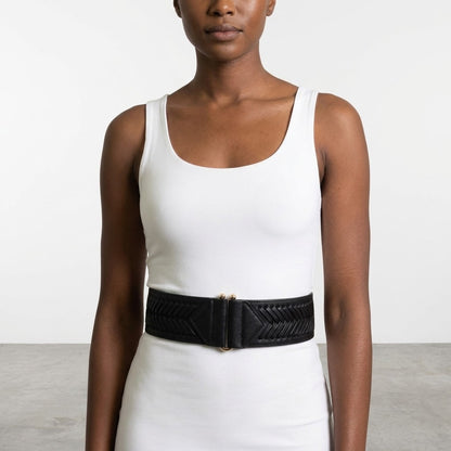 Woman in white dress with wide black belt, minimalistic background.