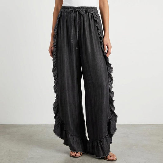 Wide-leg ruffled black pants with a white top.