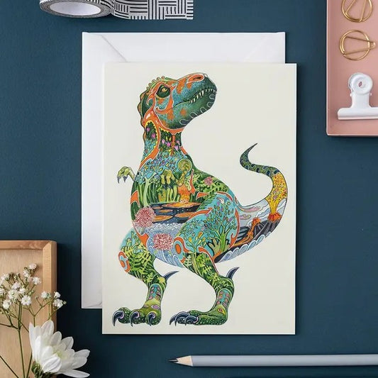Colorful dinosaur art card on a desk with stationery.