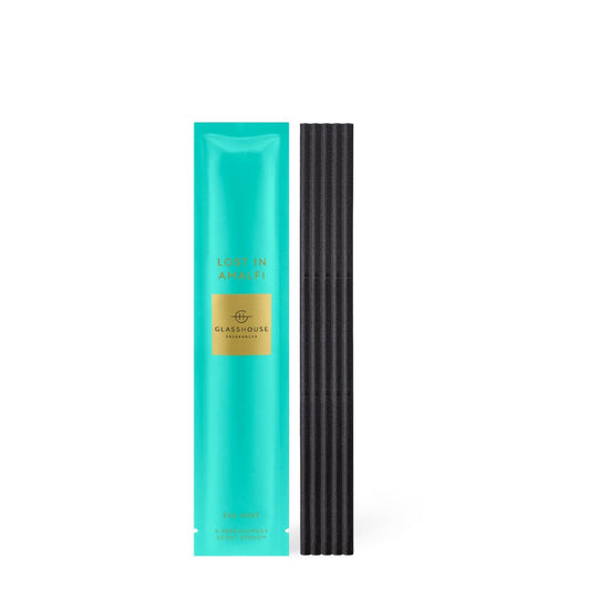 Turquoise package labeled "Lost in Amalfi" next to black incense sticks.