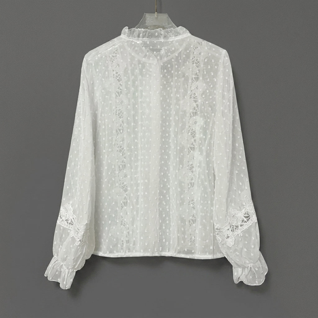 White lace blouse with polka dot design and frilly cuffs.