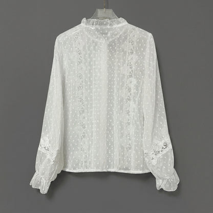 White lace blouse with polka dot design and frilly cuffs.