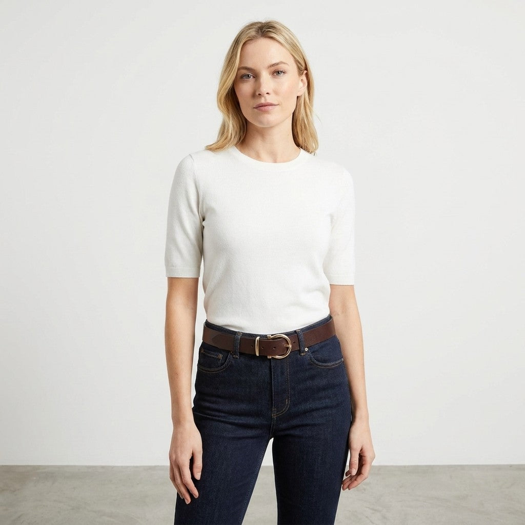 Person in a white shirt and jeans against a plain background.