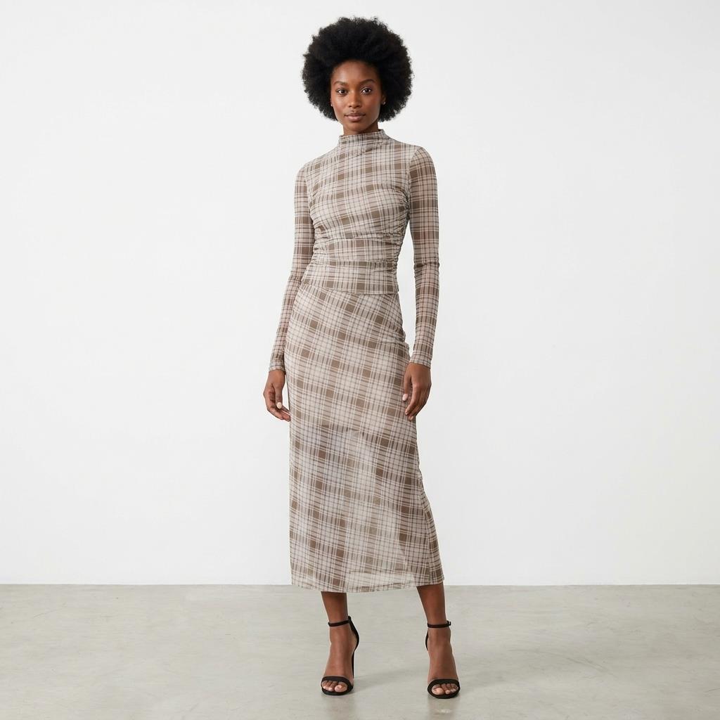 Woman in a plaid, form-fitting dress and heels on a plain backdrop.