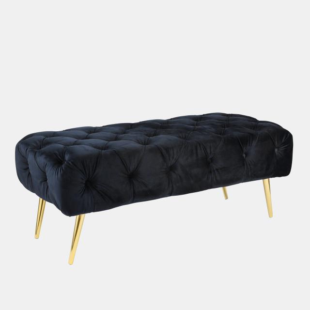 A black tufted velvet bench with elegant gold legs.