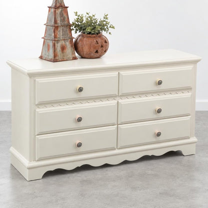 Cream dresser with six drawers, topped with rustic decor and a plant.