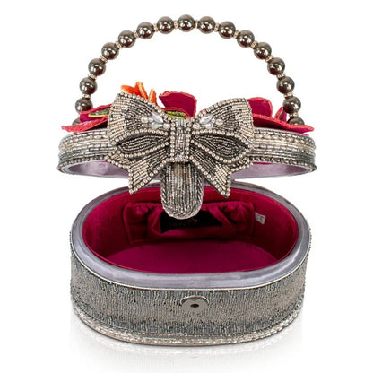 Beaded clutch with bow, floral accents, and metallic handle, open to reveal red interior.