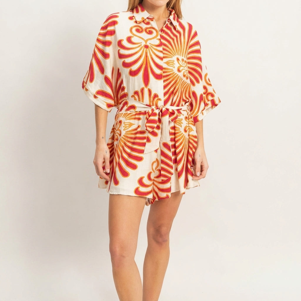 Woman in a floral print romper posing indoors.