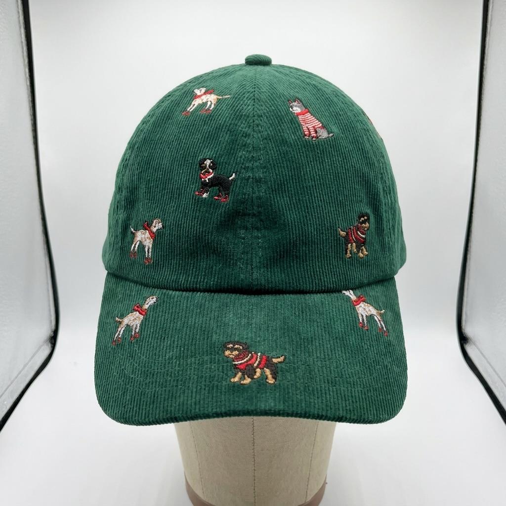 A green corduroy cap embroidered with playful dogs, displayed on a mannequin.
