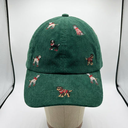 A green corduroy cap embroidered with playful dogs, displayed on a mannequin.