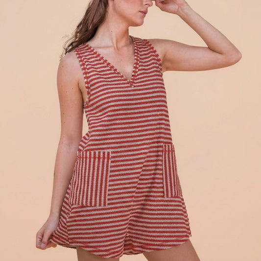 Model in a red striped sleeveless dress, hand shielding eyes.