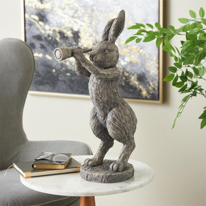 Rabbit statue with telescope on table, next to chair and plants.