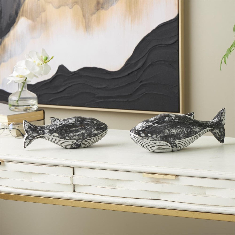 Decorative whale sculptures on a white tabletop with a modern painting behind.