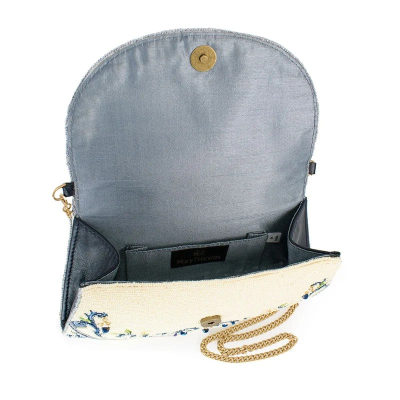 Open handbag with floral design and gold chain strap.
