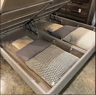Opening bed storage with pillows and blankets inside.