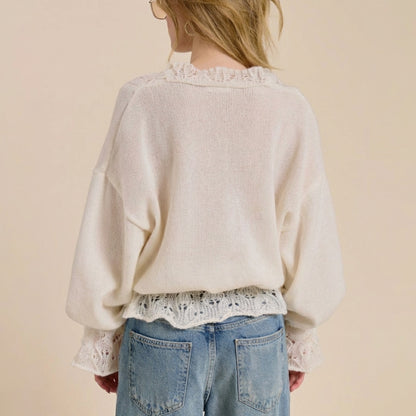 Person in lace-trimmed sweater, light jeans, and glasses, facing away.