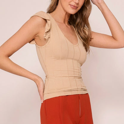 Woman in beige top and red pants against a plain background.