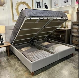Storage bed frame with mattress lifted, revealing storage space underneath.