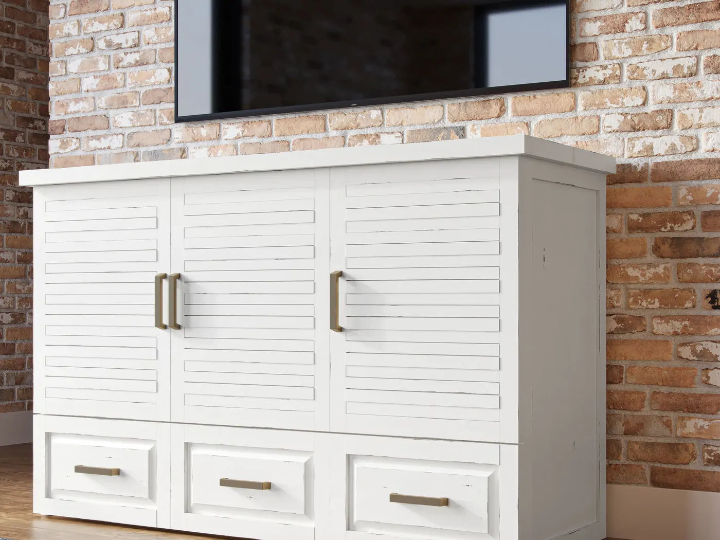 White Saugatuck cabinet bed, closed, under a TV against a brick wall