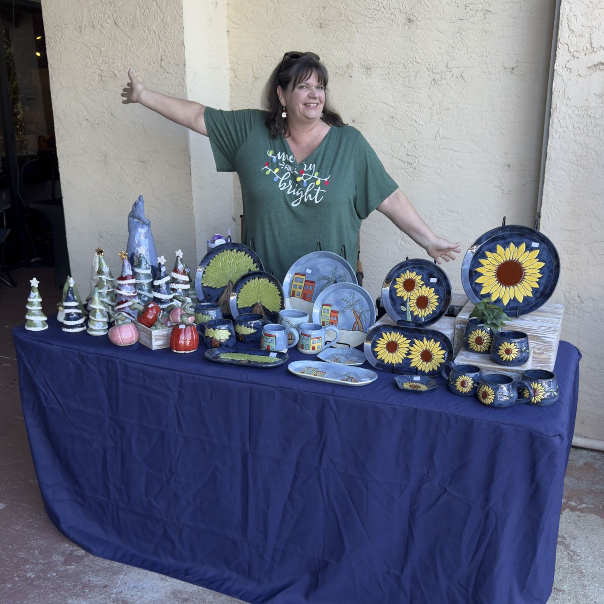 A vendor behind a table of hand-painted sunflower ceramics under the overhang