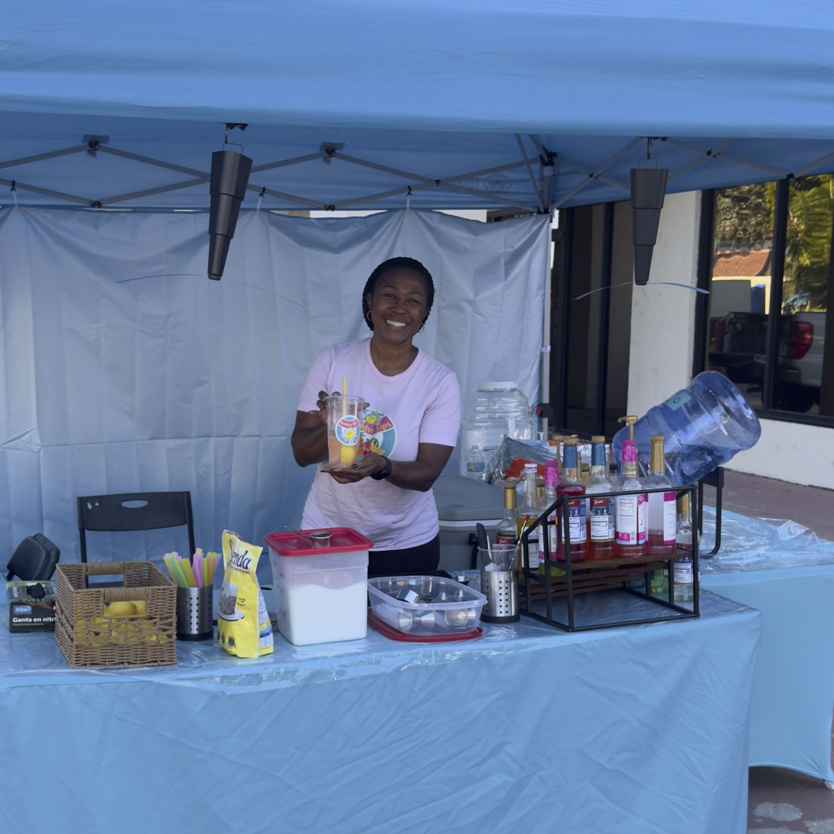 A vendor under a blue tent with a table of handmade goods